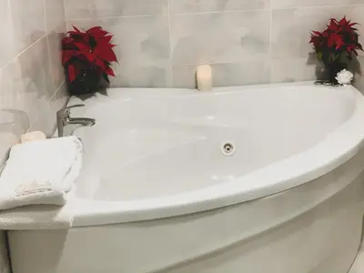 a white bath tub in a bathroom with red plants at Atlantic Hotel - Free Parking in Sofia
