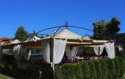 an outdoor patio with white umbrellas and tables at Hotel Gloria Palace Diplomat in Sofia
