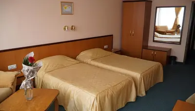 a hotel room with two beds and a table at Troyan Plaza Hotel in Troyan