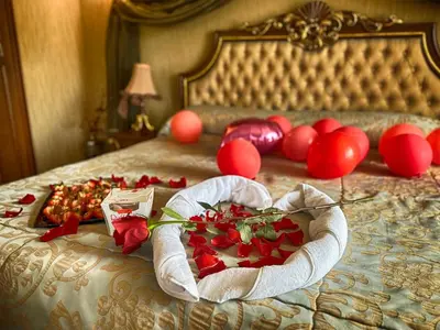 a bed with a heart shaped box of roses and balloons at Spa Hotel Rich in Velingrad