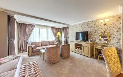 a hotel room with a bed and a couch and a television at Spa Hotel Rich in Velingrad