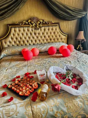 a bed with a tray of food and red balloons at Spa Hotel Rich in Velingrad