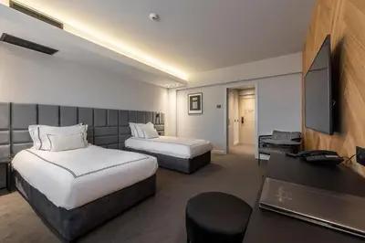 a hotel room with two beds and a desk at Hotel VEGA Sofia in Sofia