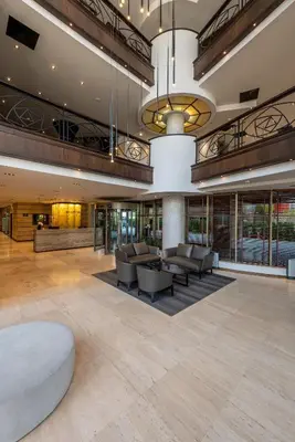 an open lobby with couches and tables in a building at Hotel VEGA Sofia in Sofia