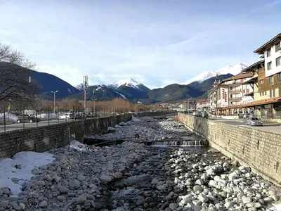 a river in a city with mountains in the background at Fortuna Luxury Apartment in Bansko