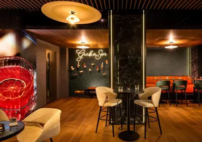 a restaurant with a bar with white chairs and a table at Rosslyn Central Park Hotel Sofia in Sofia