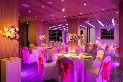 a banquet hall with white tables and chairs and purple lighting at Rosslyn Central Park Hotel Sofia in Sofia