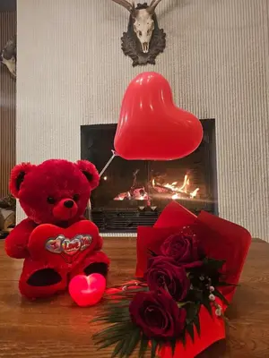 a red teddy bear sitting next to a bouquet of roses at The Lodge Hotel in Borovets