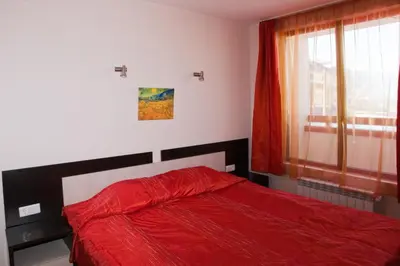 a bedroom with a red bed and a window at Mountview Lodge Apartments in Bansko