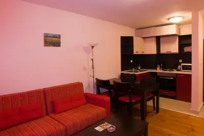 a living room with a red couch and a kitchen at Mountview Lodge Apartments in Bansko