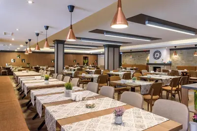 a dining room with tables and chairs and lights at Lion Hotel Borovets in Borovets