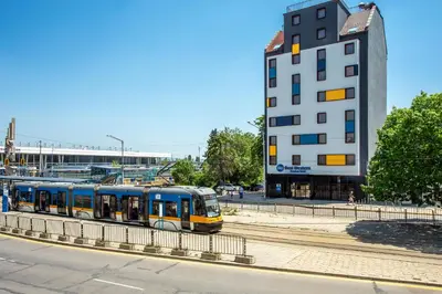 a blue and yellow train on tracks next to a building at Best Western Terminus Hotel in Sofia