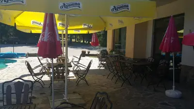 a group of tables and chairs under an umbrella at Hotel Via Trayana in Beli Osŭm