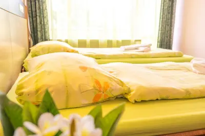 two beds in a bedroom with yellow sheets and flowers at Hotel Gorna Banya in Sofia