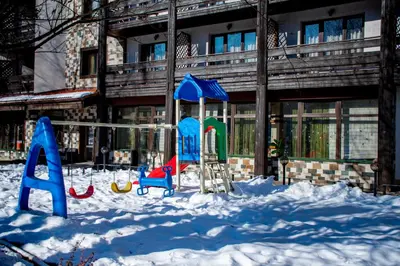 a playground in the snow in front of a building at Hotel Orphey in Bansko