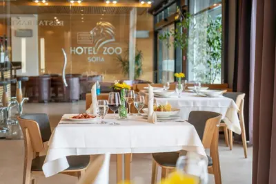 a table with white tables and chairs with plates of food at Hotel ZOO Sofia in Sofia