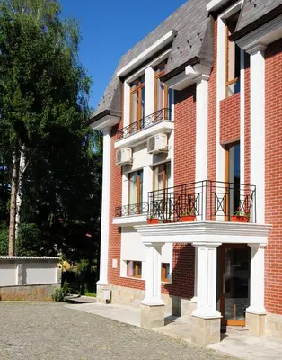 a red brick building with a balcony on it at Chateau Montagne Hotel Troyan in Troyan