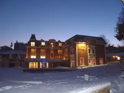 a large building in the snow at night at Chateau Montagne Hotel Troyan in Troyan