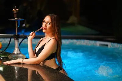 a woman in a bikini brushing her teeth in a swimming pool at Hotel Central Club Sofia in Sofia