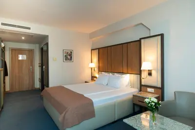 a hotel room with a large bed and a chair at Legends Hotel in Sofia