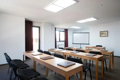 a classroom with wooden tables and chairs and a screen at Legends Hotel in Sofia