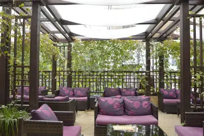 a pergola with purple couches and plants at Gardenia Park Hotel in Bansko