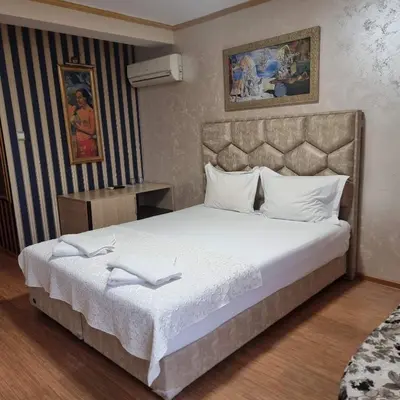 a bedroom with a large bed with white sheets at Hotel Gabi in Plovdiv