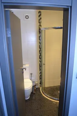 a bathroom with a toilet and a glass shower door at Elate Plaza Hotel in Sofia