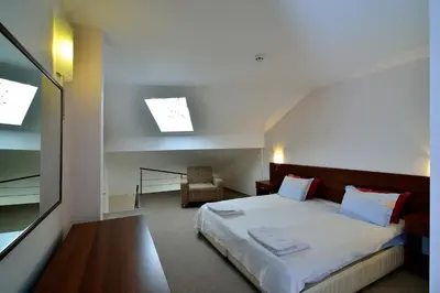 a bedroom with a large bed and a chair at Kralev Dvor Hotel in Bansko