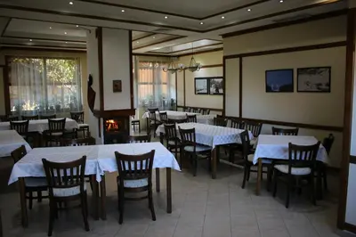 a restaurant with white tables and chairs and a fireplace at Kralev Dvor Hotel in Bansko