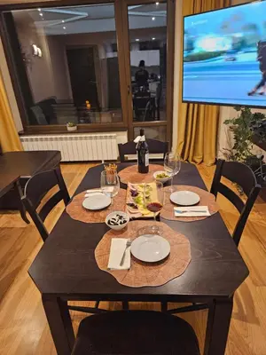 a wooden table with plates and wine glasses and a television at TERRA COMPLEX D4 - Private apartment - Golf, Skiing & SPA in Bansko
