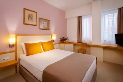 a bedroom with a bed with yellow pillows and a television at Arte Sofia Hotel in Sofia