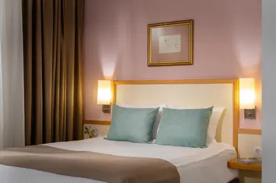 a bedroom with a bed with two blue pillows at Arte Sofia Hotel in Sofia
