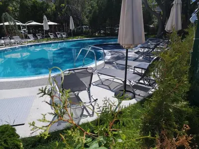 a group of chairs and umbrellas next to a swimming pool at Hotel Rila in Dupnitsa