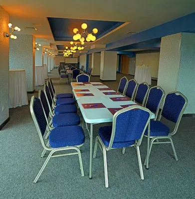 a conference room with a long table and blue chairs at Hotel Rila in Dupnitsa