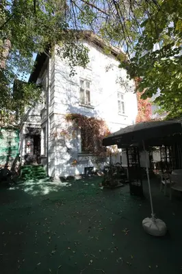 a large white building with a umbrella in front of it at Hotel & Restaurant The House in Sofia