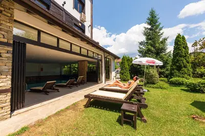 a woman laying on a bench on a patio with an umbrella at Hotel Bansko SPA & Holidays - Free Parking in Bansko