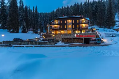 a large house in the snow at night at The Stream Resort Pamporovo in Pamporovo