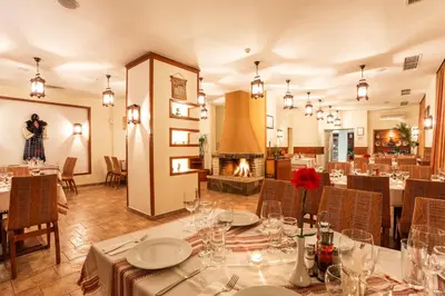 a dining room with tables and chairs and a fireplace at The Stream Resort Pamporovo in Pamporovo