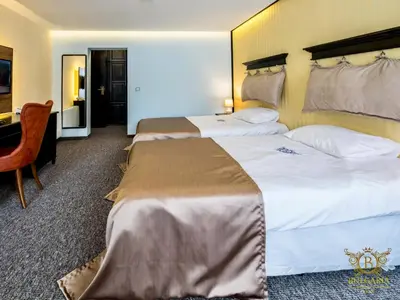 a hotel room with two beds and a desk at Wellness Hotel Bulgaria in Bansko