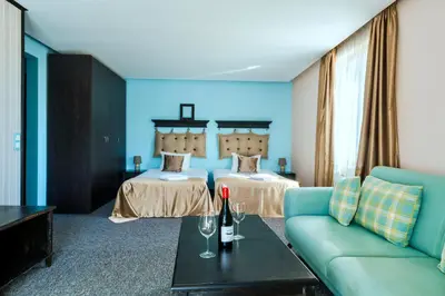 a hotel room with two beds and a couch at Wellness Hotel Bulgaria in Bansko