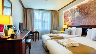 a hotel room with two beds and a desk at Platinum Hotel and Casino Bansko in Bansko