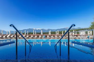 a swimming pool with chairs and blue water at Katarino SPA Hotel in Bansko