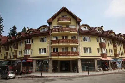 a large yellow building with a brown roof at Royal Plaza Apartments Borovets in Borovets