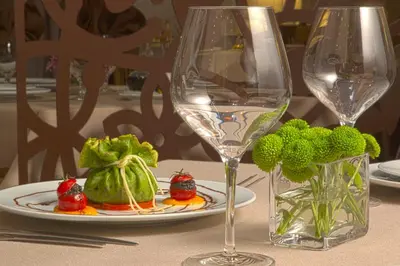 a table with a plate of food and a wine glass at Triada Hotel in Sofia