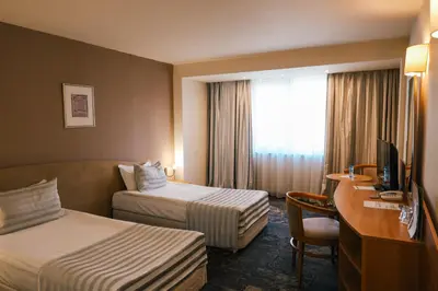 a hotel room with two beds and a desk and a television at Triada Hotel in Sofia
