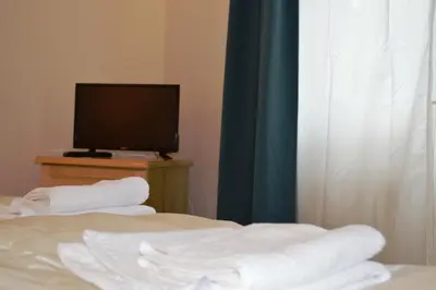 a room with a bed and a television and towels at Horizont Dobrinishte in Dobrinishte