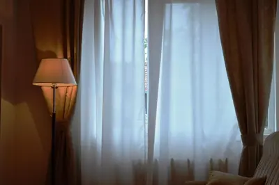 a window with white curtains next to a lamp at Horizont Dobrinishte in Dobrinishte