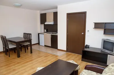 a living room with a table and a kitchen at Sunrise Park Hotel Bansko - Free Wellness in Bansko