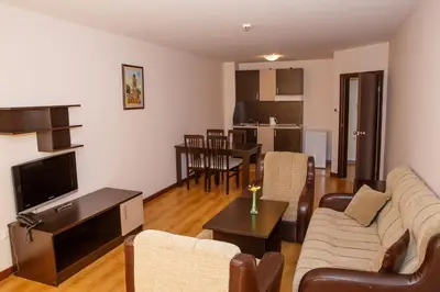a living room with a couch and a tv and a table at Sunrise Park Hotel Bansko - Free Wellness in Bansko
